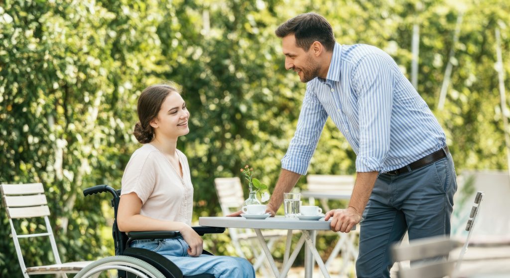 Outdoor cafe scene with man and woman in wheelchair conversing